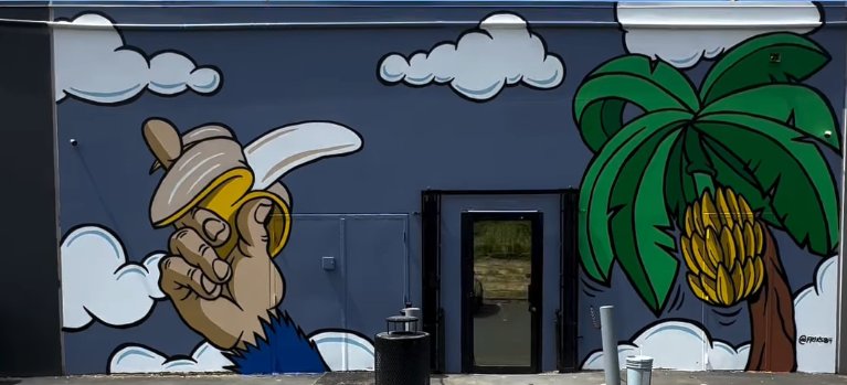 The painted exterior wall of the Kirkland shop β a cartoon ape holding a banana at one end, a banana palm at the other.